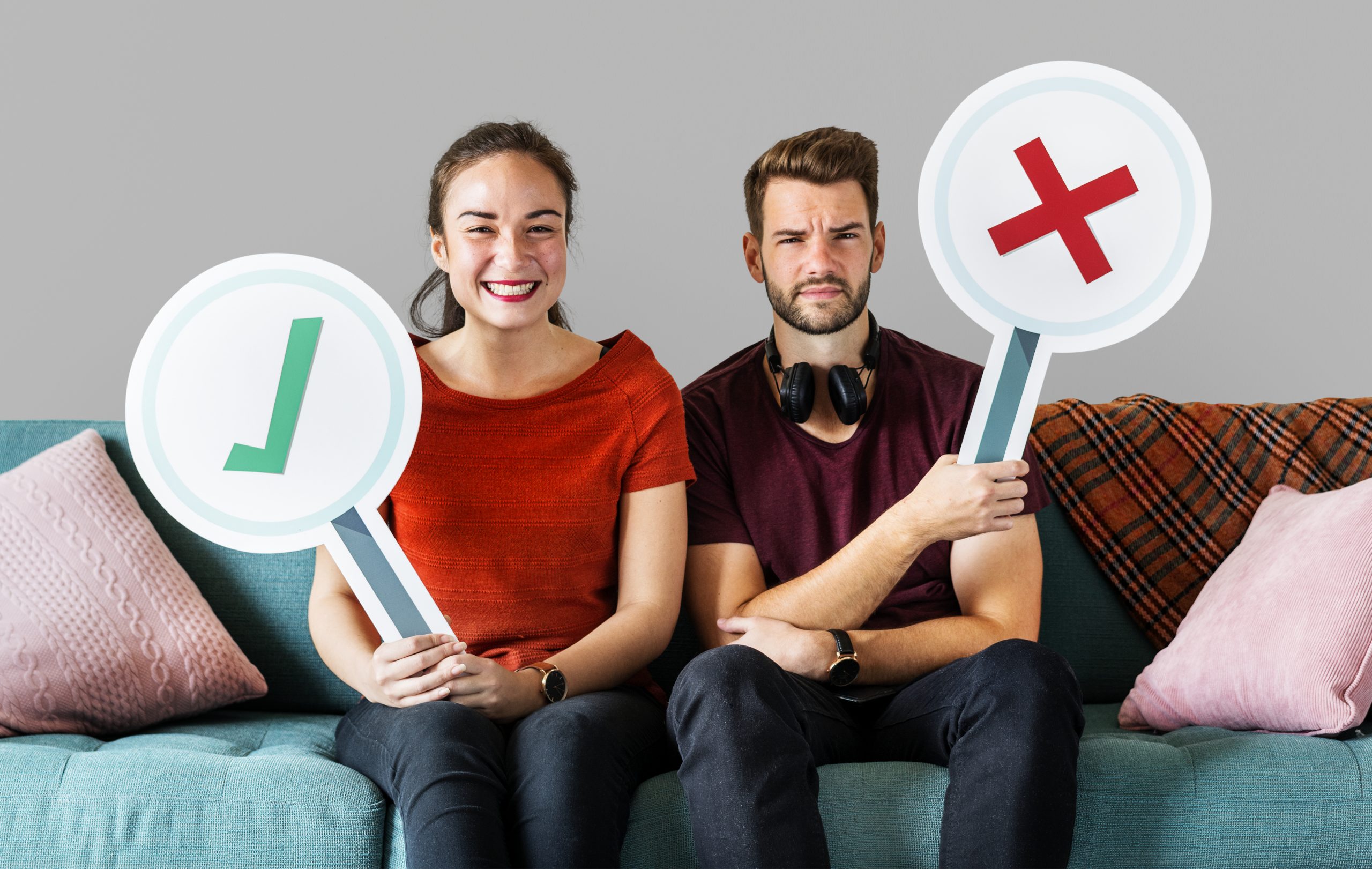 cheerful couple holding vote icon sitting on a couch